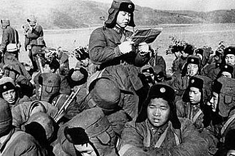 行军途中休息时，雷锋给大家读报纸。(根据雷锋《解放后我有了家，我的母亲就是党》中“......我自告奋勇要当一名兼职小教员。我教高小语文课和算术课，多数同志反映