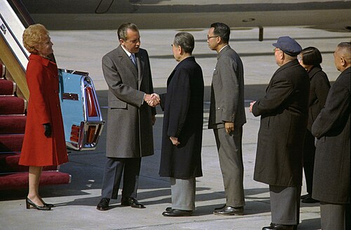 1972年2月，走下舷梯的美国总统尼克松与中国国务院总理周恩来握手寒暄。这张照片其后成为冷战的标志性画面之一。图左是夫人帕特·尼克松。